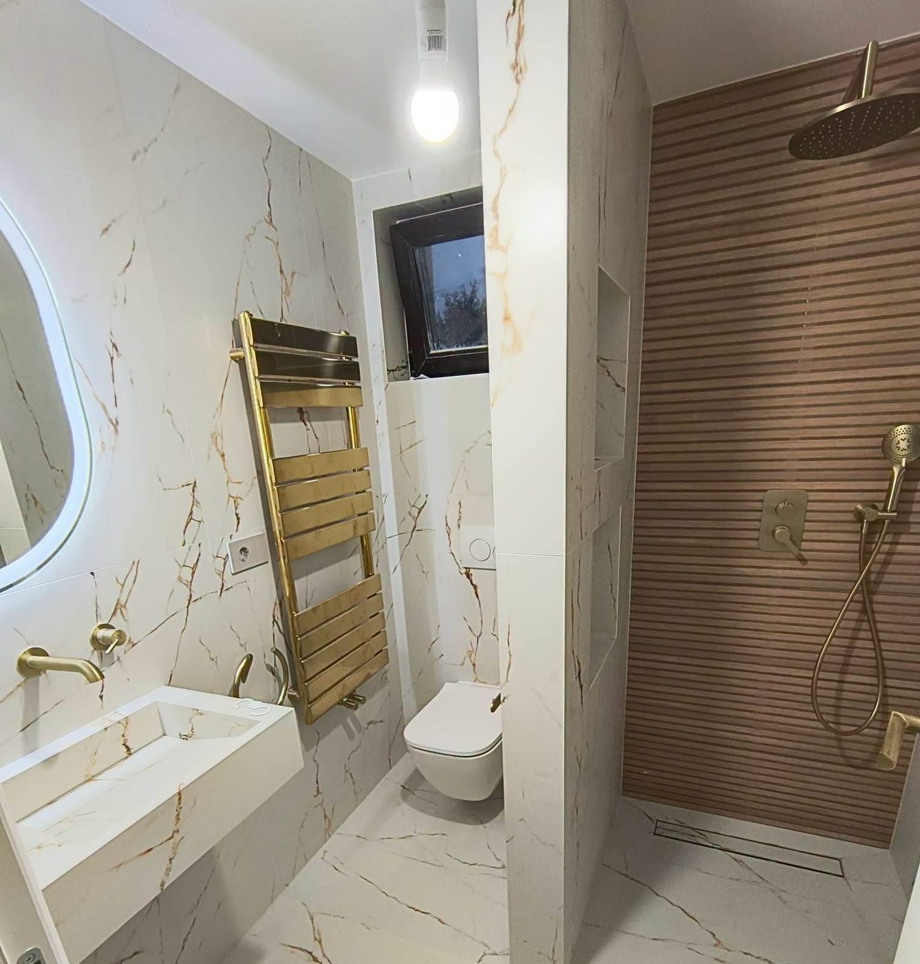 Finished bathroom with marble-effect tiles, brushed-brass fittings and a wood-slat shower wall