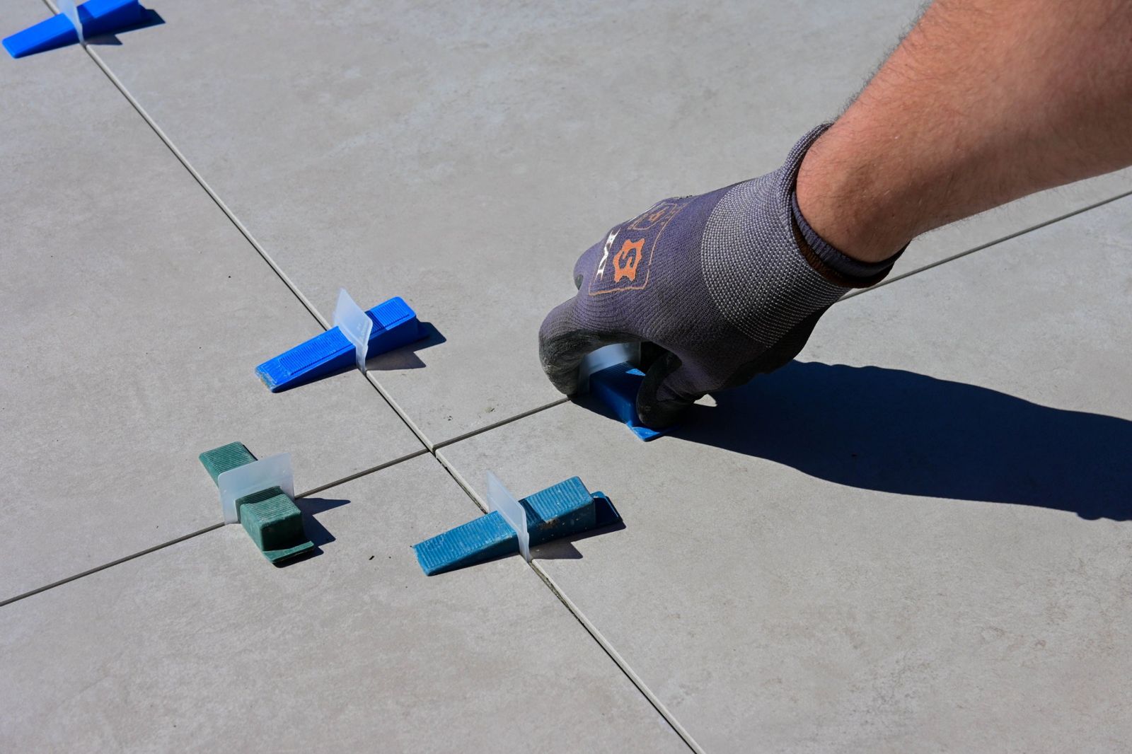 Hand placing a tile levelling spacer on floor tiles